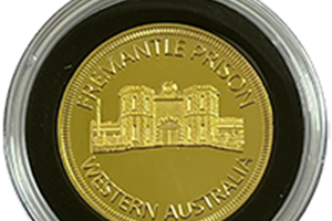 Gold plated souvenir coin featuring Fremantle Prison logo and embossing in display case